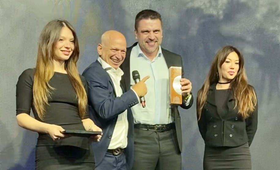 O jornalista e apresentador da TV Bandeirantes, Elia Júnior, entrega prêmio ao diretor-presidente da Lottopar, Daniel Romanowski.